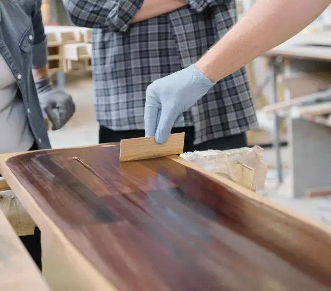 closeup-of-workers-hand-covering-wooden-plank