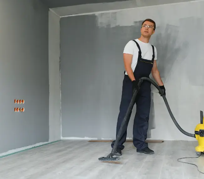 male-worker-in-overall-vacuum-cleaning-during-apartment